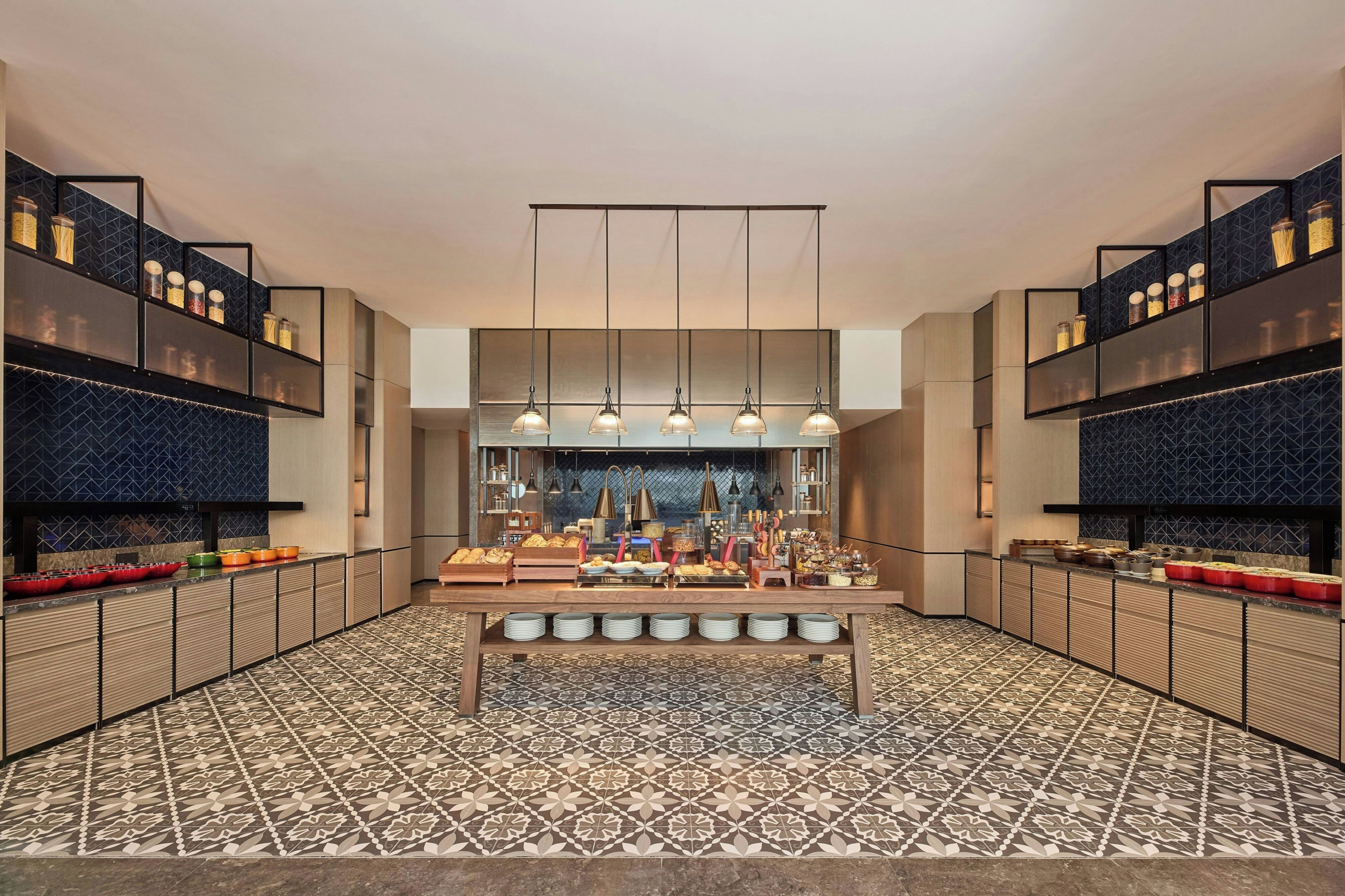 Cozinha moderna com ilha central, luminárias pendentes e piso estampado.