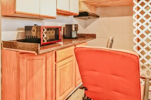 A compact kitchen with a microwave, toaster, and a red chair. - Essex Smart Stay - Torner Road (Essex)