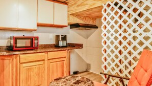 A compact kitchen with wooden cabinets, a microwave, a coffee maker, and a small round table. - Essex Smart Stay - Torner Road (Essex)