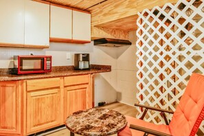 A compact kitchen with wooden cabinets, a microwave, a coffee maker, and a small round table. - Essex Smart Stay - Torner Road (Essex)