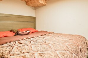 A bed with a patterned bedspread and pillows, a wooden headboard, and a plain wall. - Essex Smart Stay - Torner Road (Essex)