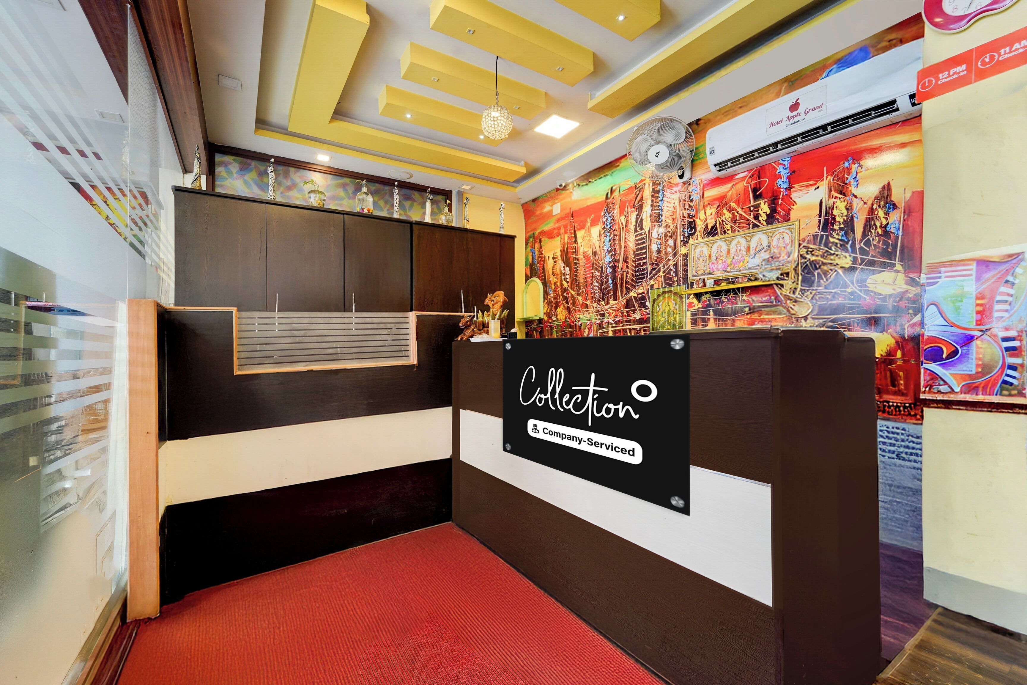 A reception desk with a 'Collection' sign, a clock, and a colorful mural in the background.