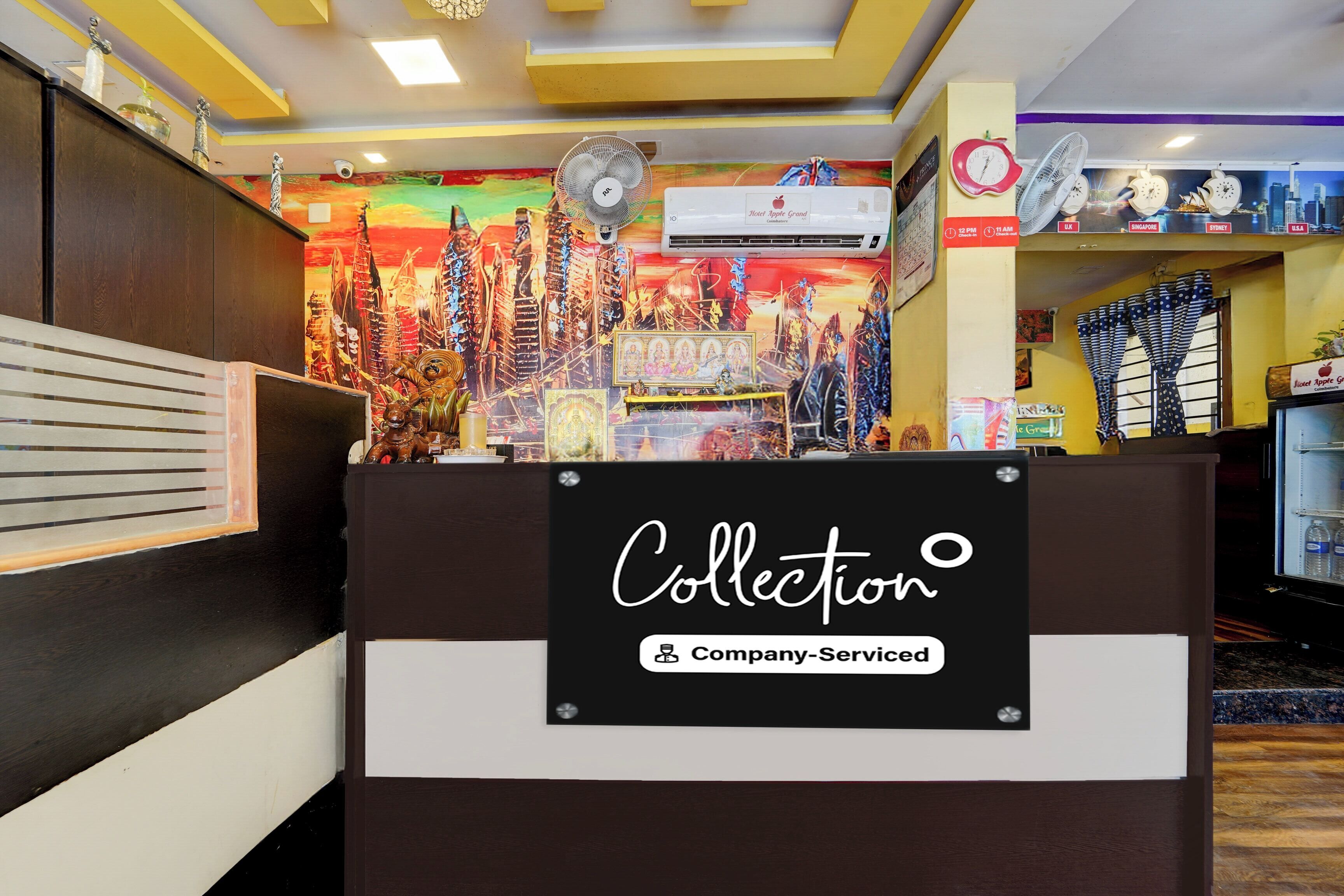 A hotel reception desk with a 'Collection' sign, a clock, and a cityscape mural in the background.