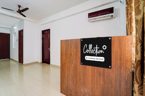 A reception area with a wooden reception desk, a ceiling fan, and an air conditioning unit. - Super Collection O Race Course Road (Coimbatore)
