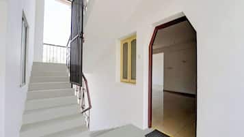 A staircase with a metal railing leading to a landing, a door with a yellow frame, and a window with a metal railing.