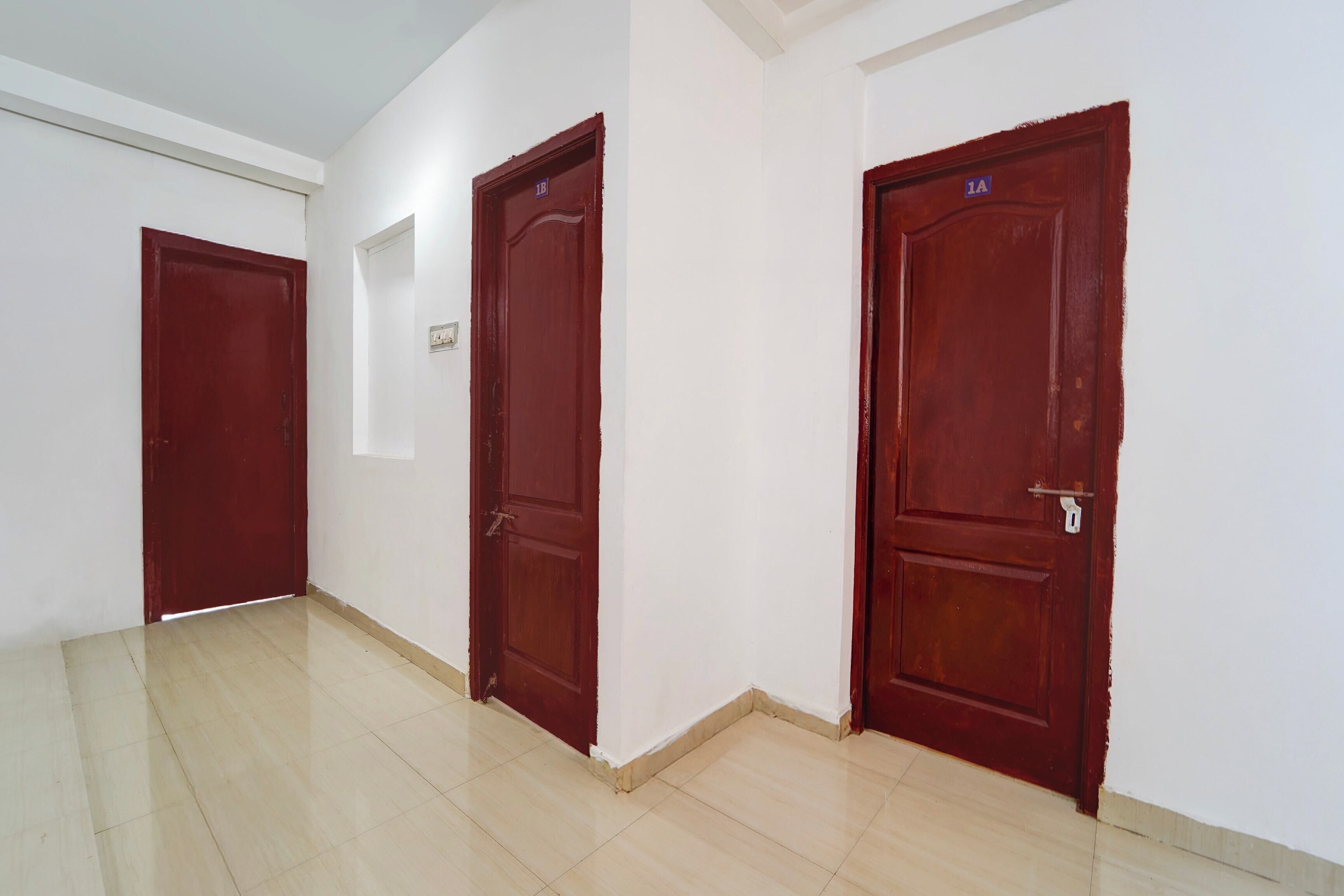 A hallway with three wooden doors, each marked with a number. The floor is tiled, and the walls are white.
