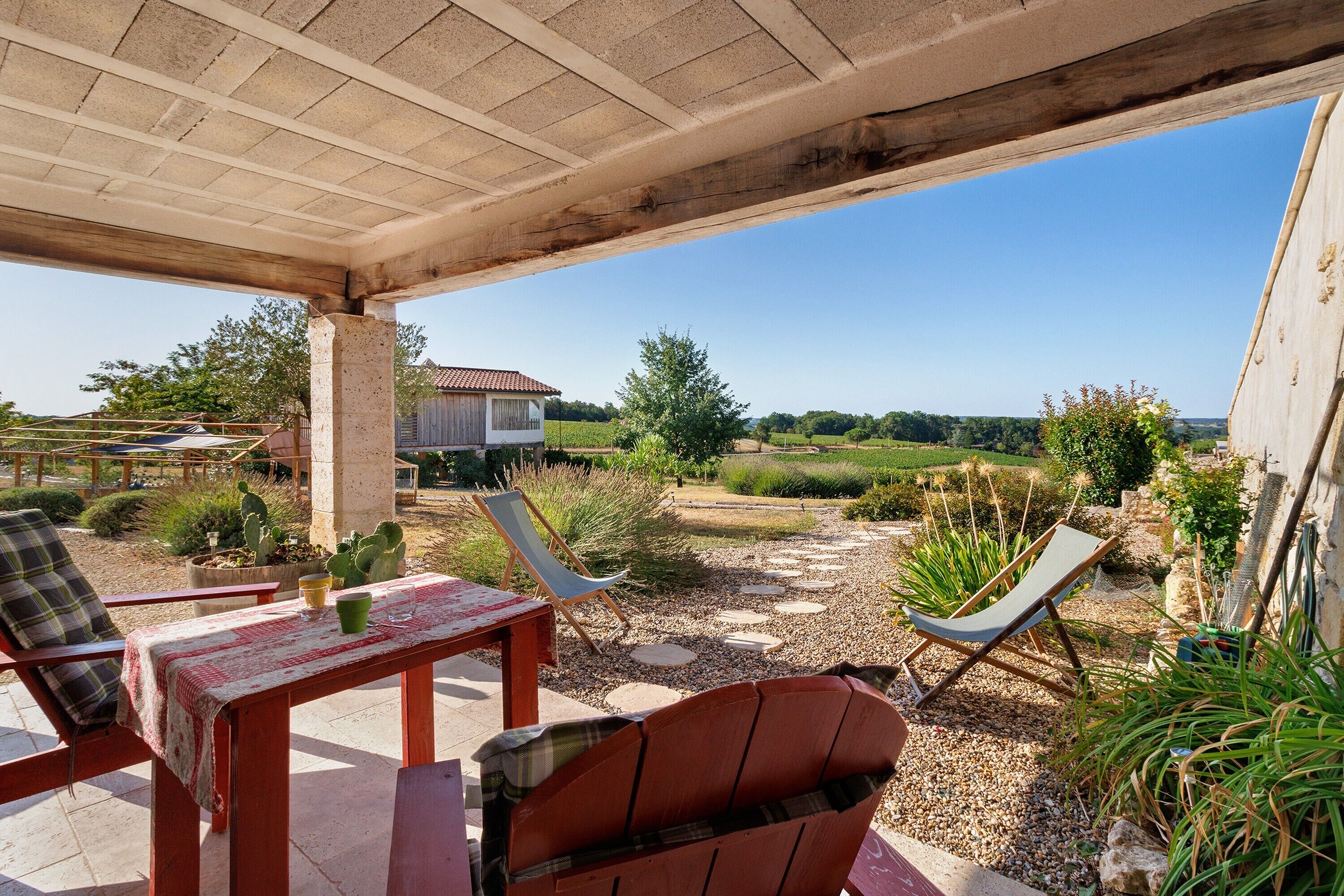 An outdoor patio with a table, two chairs, and a hammock.