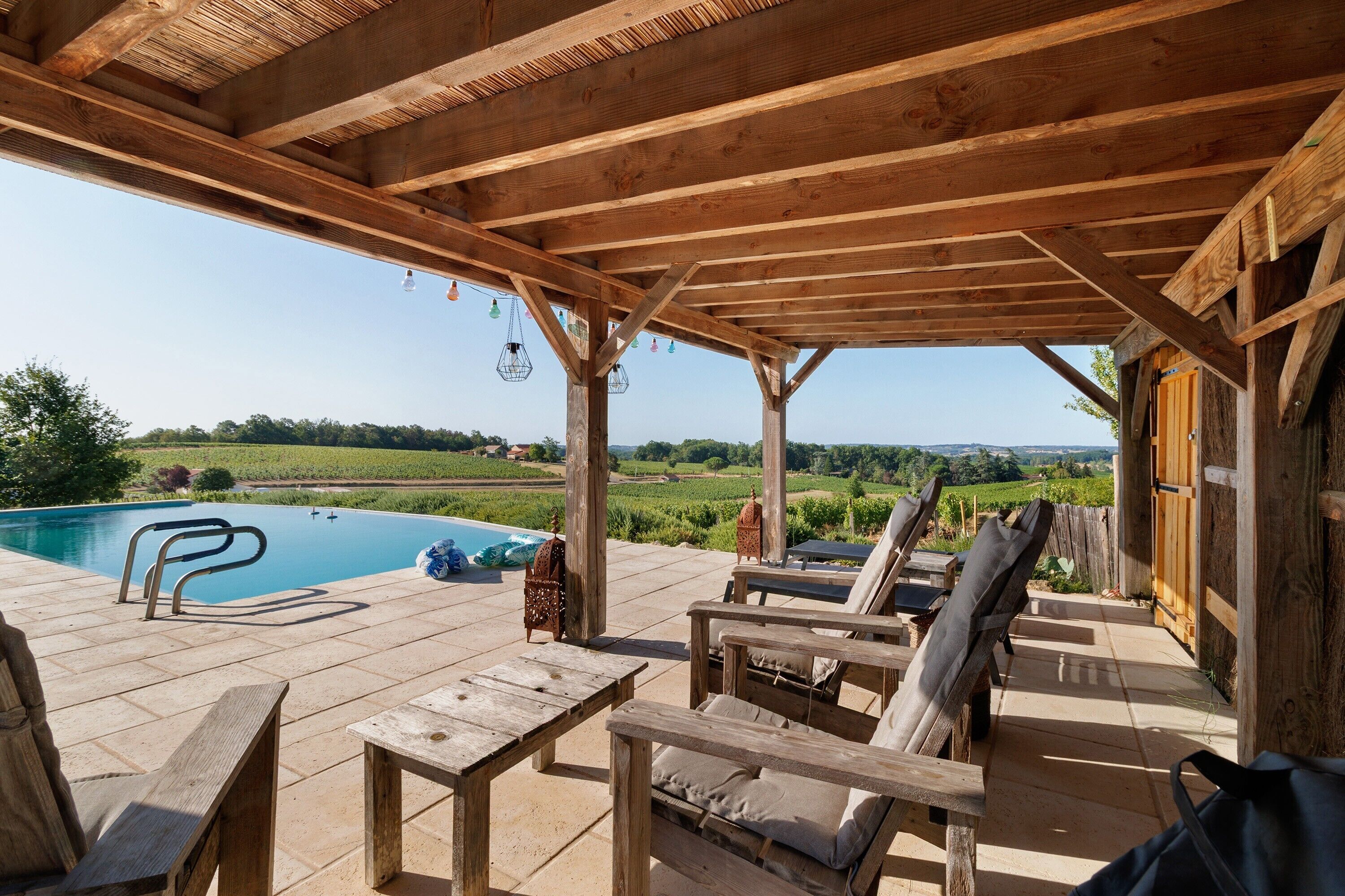 A wooden deck with a pool, lounge chairs, and a pergola.