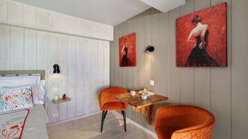 Ein Zimmer mit einem Bett, zwei Stühlen, einem kleinen Tisch mit einer Speisewanne und zwei Bildern an der Wand.