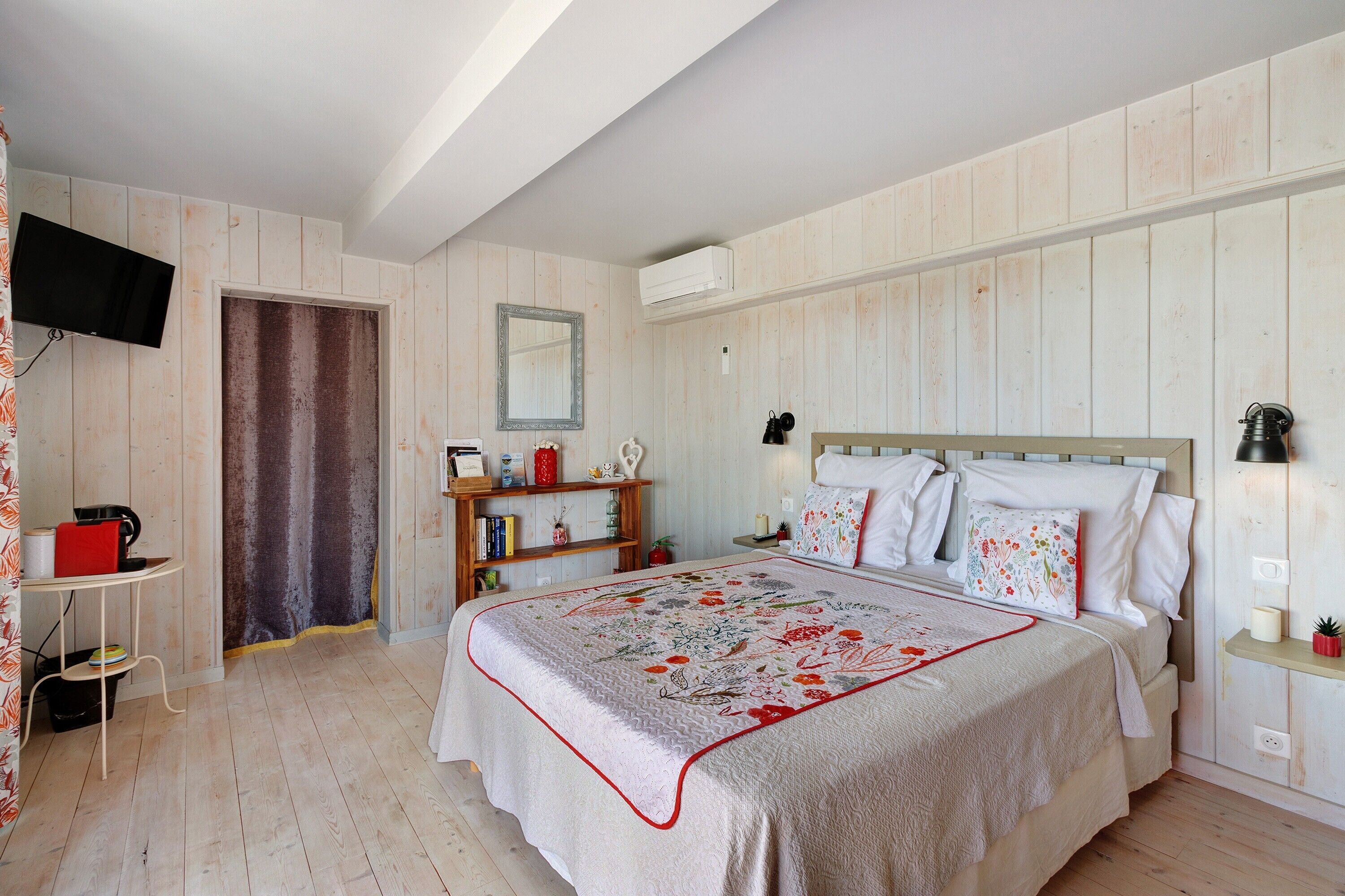 Une chambre à coucher avec un lit, des tables de chevet, une télévision et une armoire.