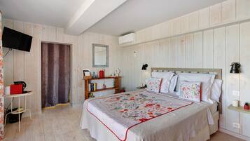 Une chambre à coucher avec un lit, des tables de chevet, une télévision et une armoire.