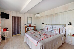 A bedroom with a bed, bedside tables, a TV, and a wardrobe.