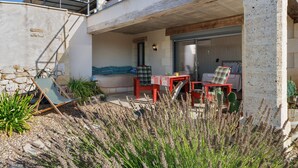 Un espace extérieur moderne aménagé avec une table et des chaises, entouré de plantes et d’un mur en pierre.