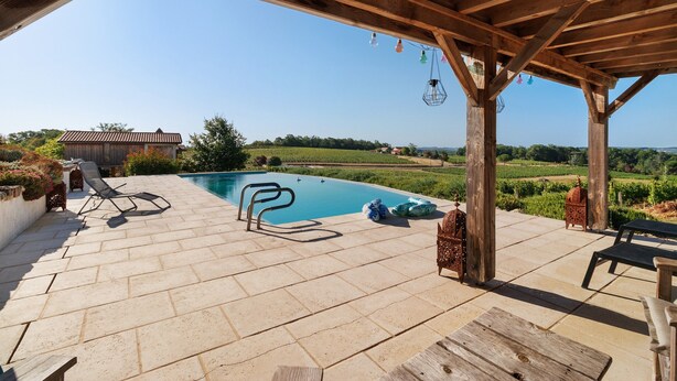 Une piscine extérieure couverte, dotée de chaises longues et d’une structure en forme de pergola.
