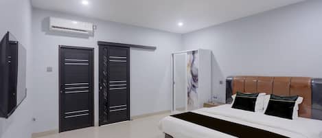 A modern bedroom with a large bed, a wardrobe, a mirror, and a flat-screen TV.