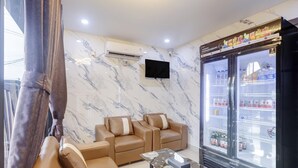 Een moderne woonkamer met een marmeren wand, een flatscreen televisie, een zithoek en een minibar.
