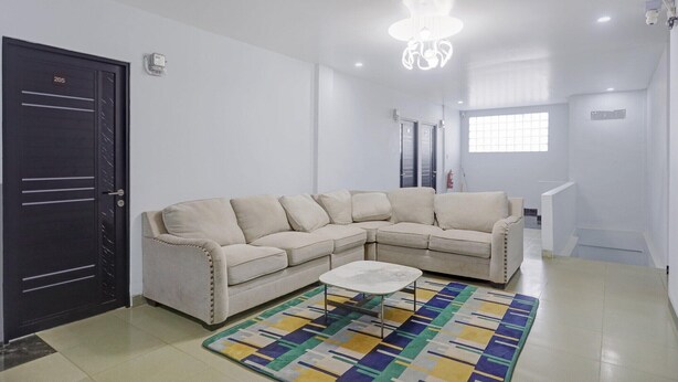 Een woonkamer met een beige modulaire bank, een salontafel en een kamerkleed met een patroon.