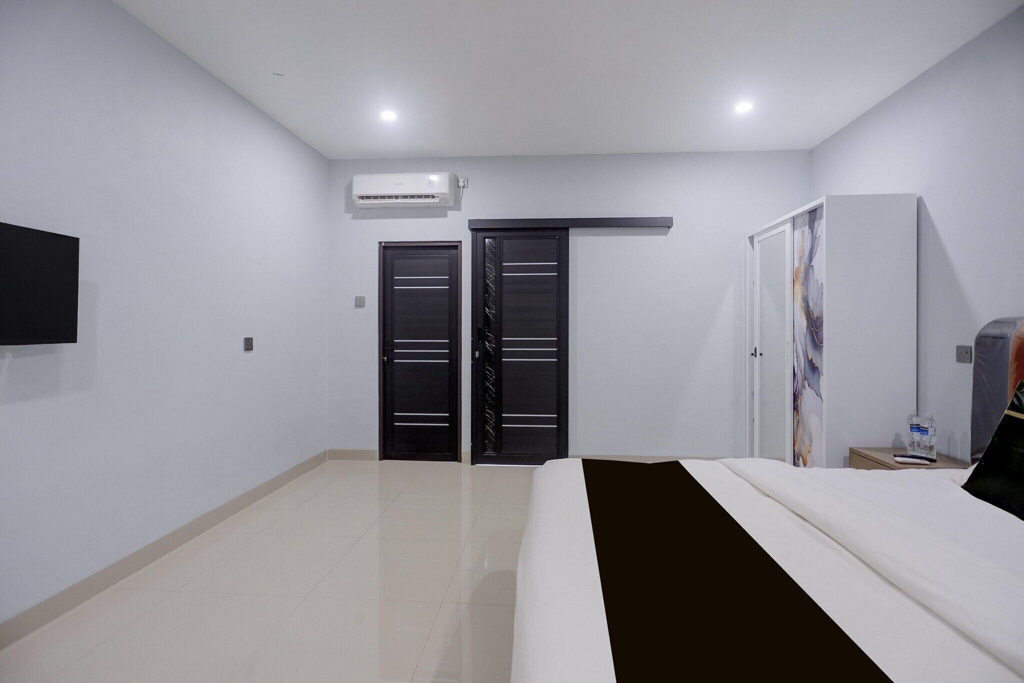 A hotel room with a bed, a flat-screen TV, a wardrobe, and a door with a handle.