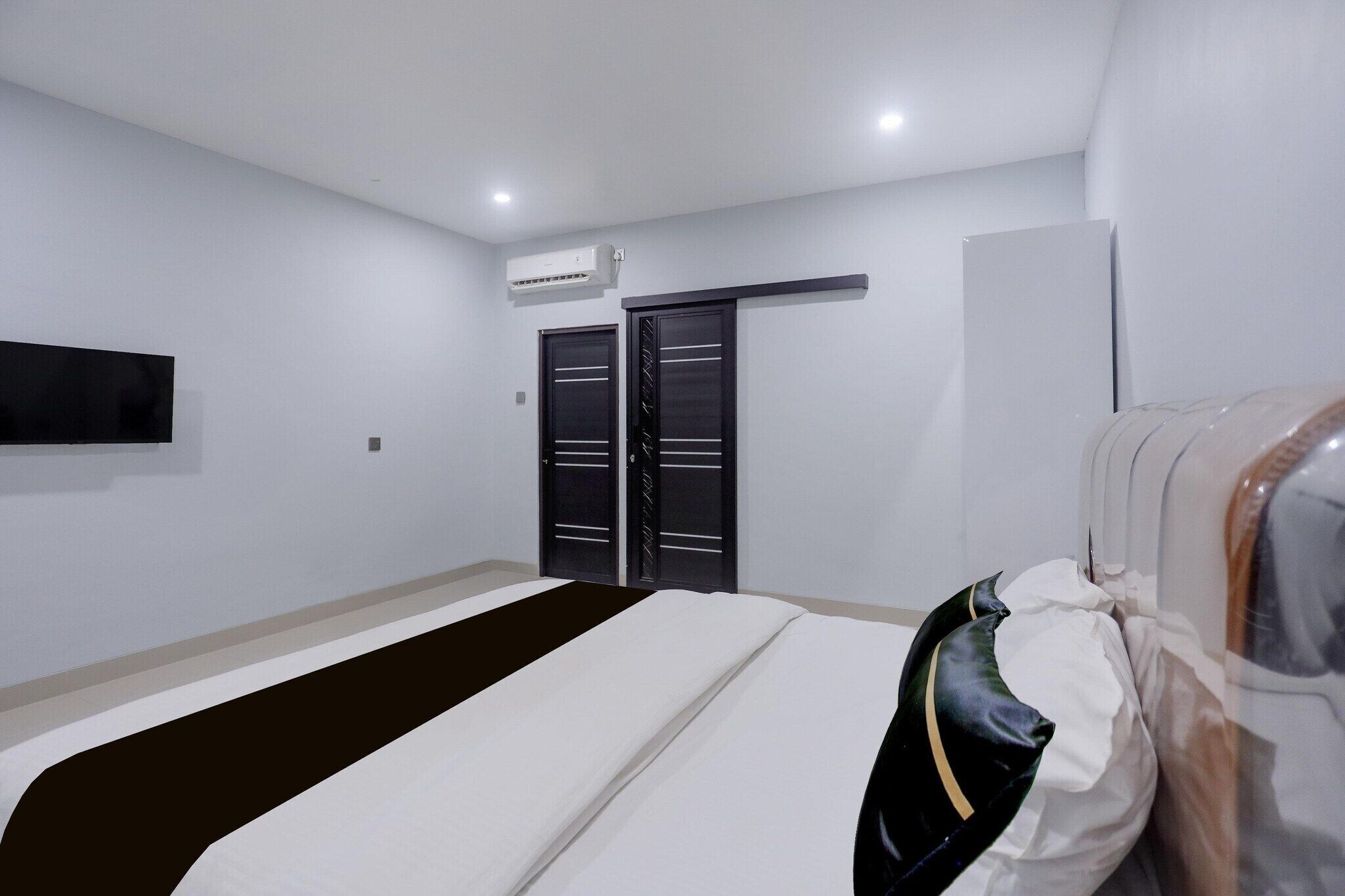 Une chambre d’hôtel équipée d’un lit, d’une armoire, d’un miroir et d’un téléviseur fixé au mur.