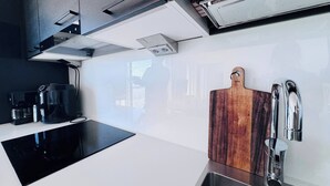 Uma cozinha moderna com bancada preta, pia de aço inoxidável e tábua de corte de madeira.