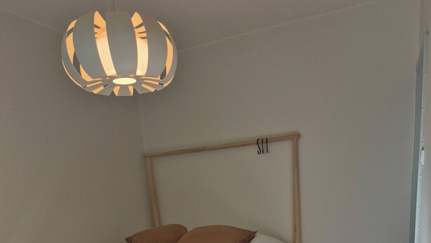 A bedroom with a wooden bed frame, a white bedspread, and two brown pillows.