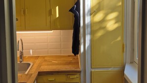 A compact kitchen with yellow cabinets, a wooden countertop, a sink, and a window.