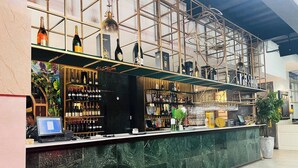 Zona de bar con estantes llenos de botellas, una computadora y una recepción.