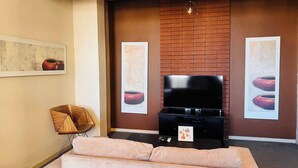 Una habitación de hotel con una cama grande, una televisión de pantalla plana y una pared decorativa de ladrillo.