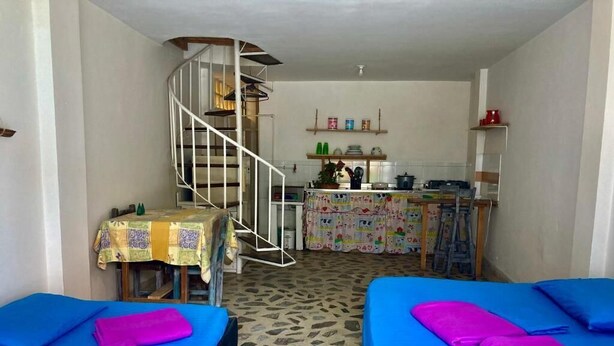 Une pièce de taille modeste comprenant deux lits, une petite cuisine et un escalier en colimaçon.