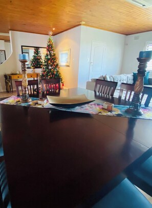 A dining area with a wooden table, chairs, a Christmas tree, and a staircase in the background. - Bonita Vista Plattekloof (Cape Town)