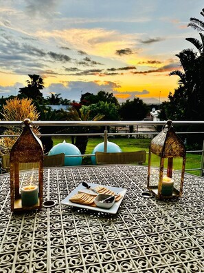 A table set with a plate of waffles and a candle, two lanterns, and a view of the sunset. - Bonita Vista Plattekloof (Cape Town)