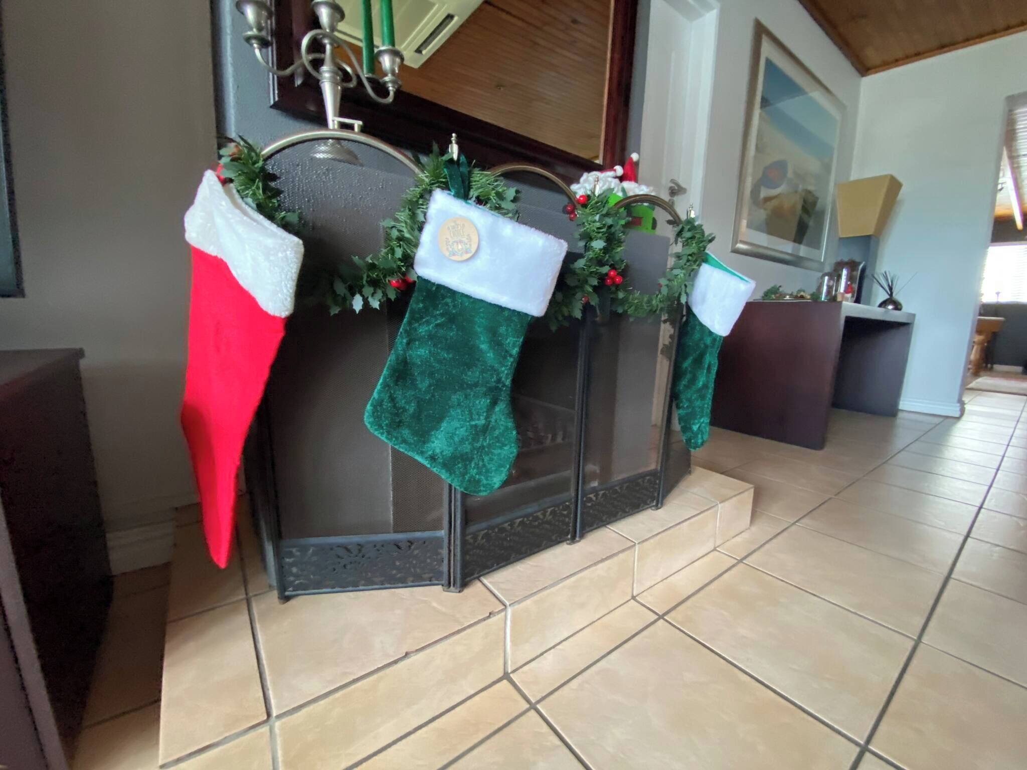 Une cheminée ornée de trois chaussettes de Noël, une rouge et deux vertes, et décorée pour les fêtes.