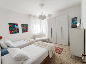A bedroom with two beds, a wardrobe, a mirror, and artwork on the walls. - Modern Apartment Near Senigallia's Velvet Beach (Senigallia)