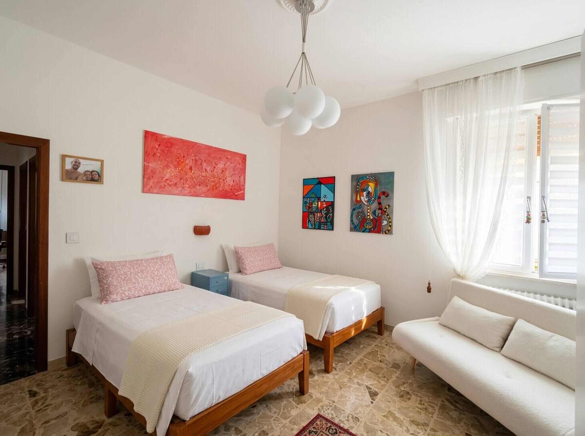 A bedroom with two beds, a sofa, and artwork on the walls.