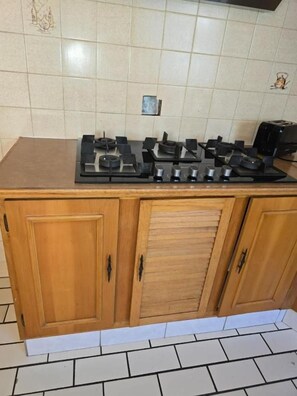 A kitchen with a gas stove, wooden cabinets, and a tiled backsplash. - Room-aquasaintsguest Lodge (Johannesburg)