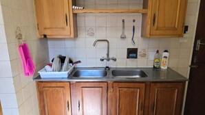 Una cocina con armarios de madera, un lavamanos doble y salpicadero de azulejos.