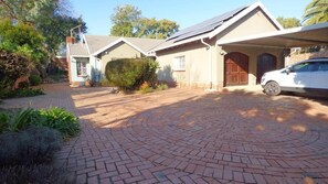 A residential property with a paved driveway, a garage, and a car parked inside. - Room-aquasaintsguest Lodge (Johannesburg)