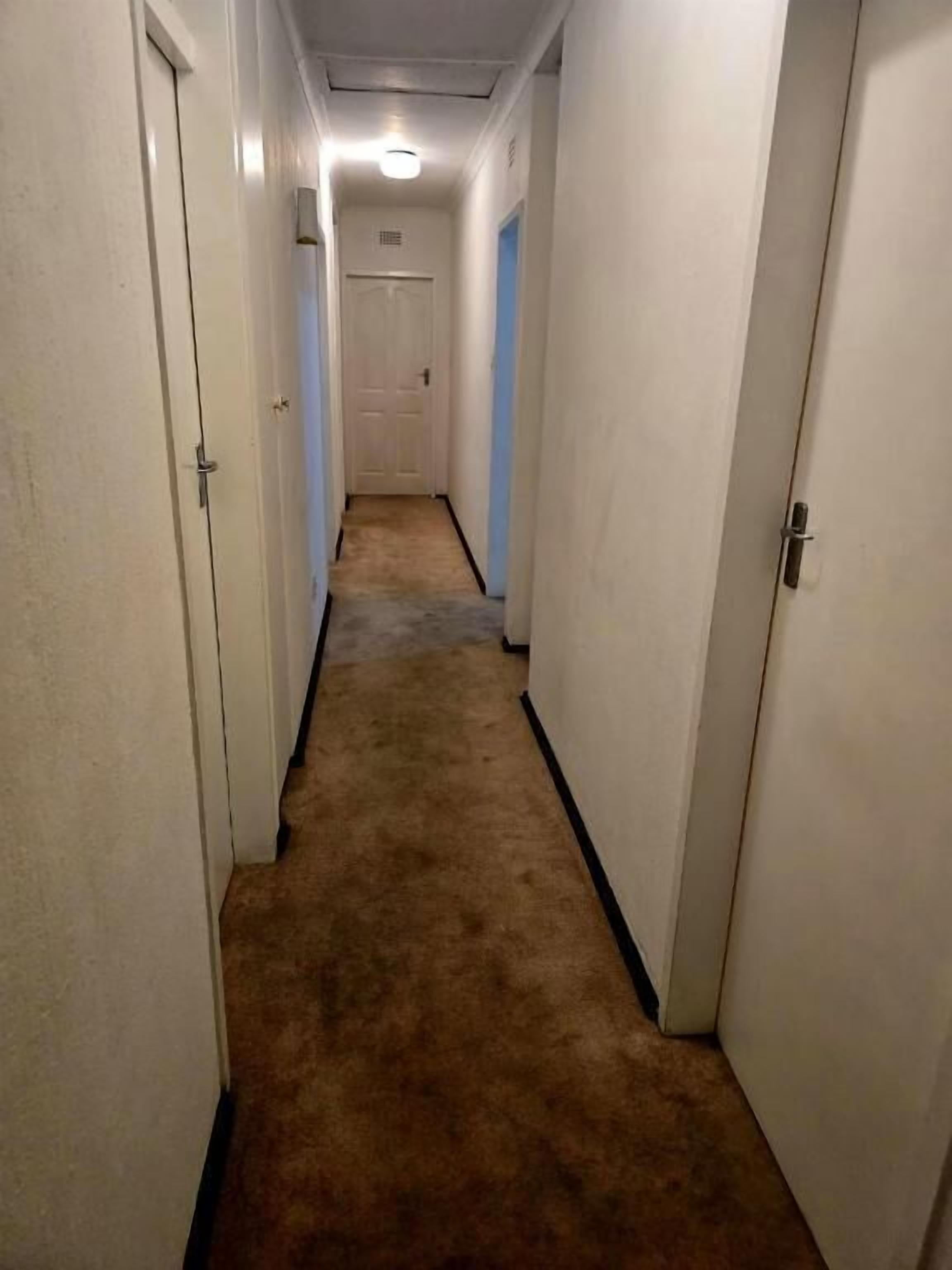A narrow hallway with carpeted floors and white walls.