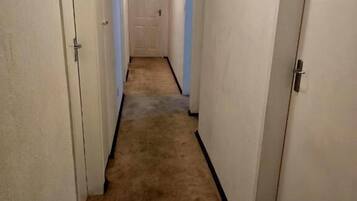A narrow hallway with carpeted floors and white walls.