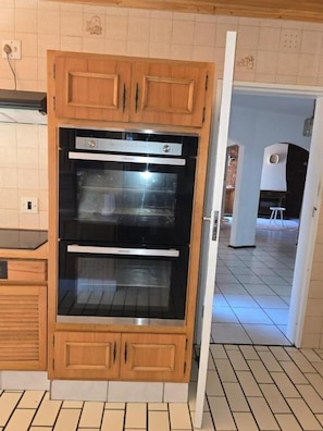Una cocina con armarios de madera, un horno doble y piso de baldosas.