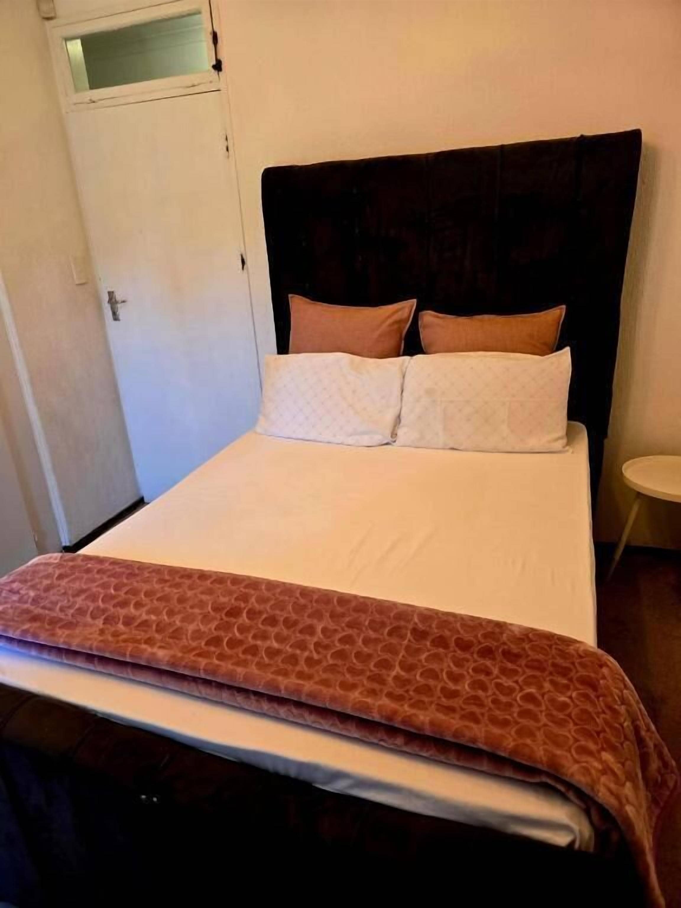 A hotel room with a bed, a door, and a small round table.