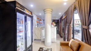 A hotel lobby with a refrigerator stocked with beverages, a reception desk, and a seating area with a sofa. - Haruasa Residence • Cozy Double (Batam)