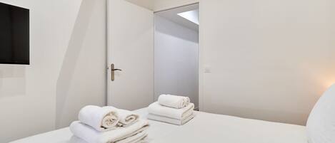 Une chambre d’hôtel avec un lit, une porte et un luminaire fixé au mur.