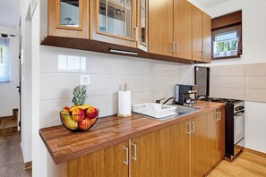Eine moderne Küche mit Holzschränken, einer Edelstahl-Spüle und einem Gasherd.