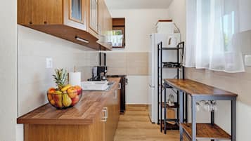 A compact kitchen with wooden cabinets, a built-in stove, and a fruit bowl on the counter.