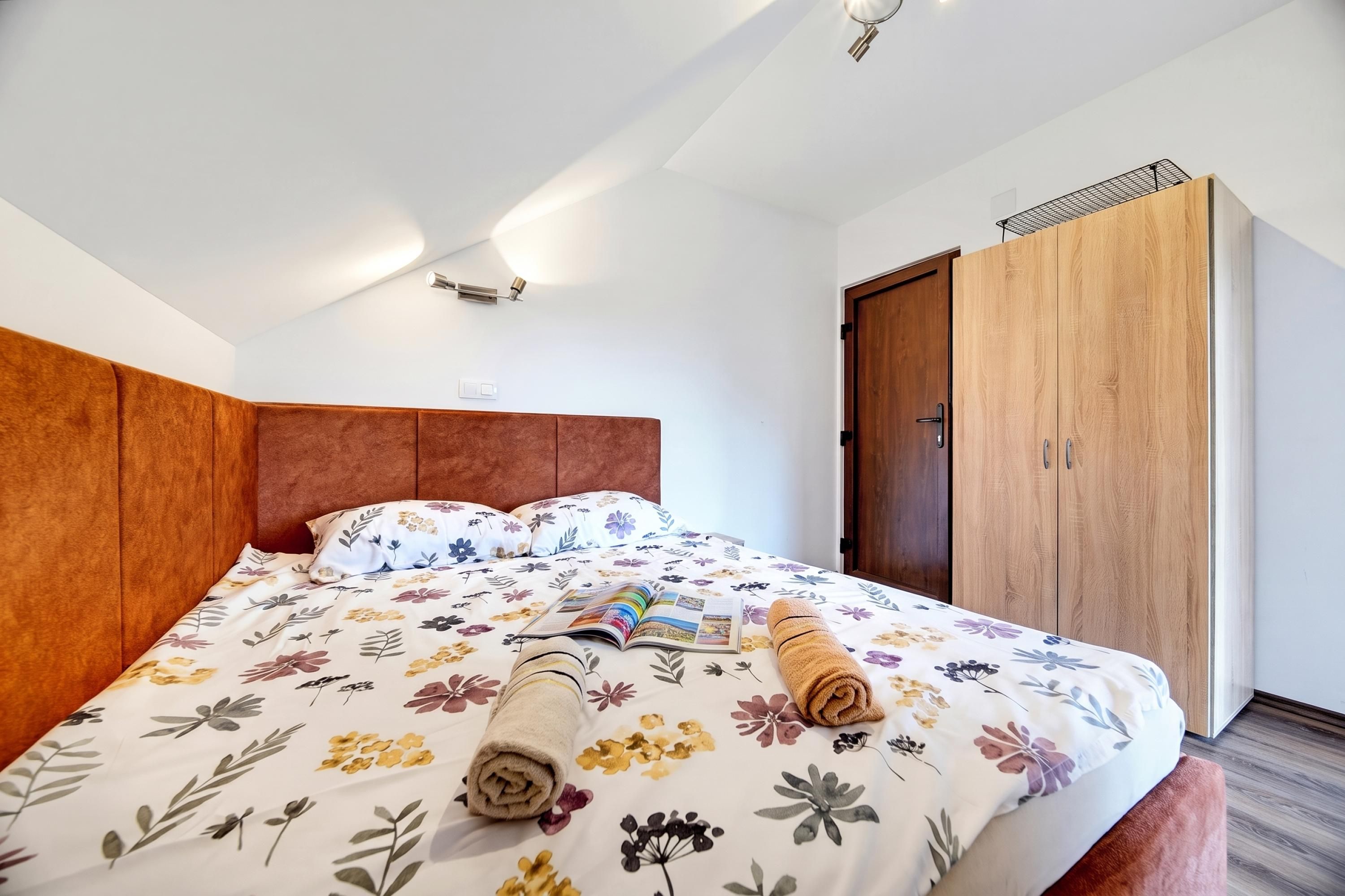 Una habitación de hotel con una cama grande, un armario de madera y una lámpara en el techo.
