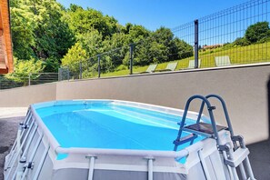 An above-ground swimming pool with a ladder, surrounded by a fence and trees. - Greenwood Retreat With Hot Tub & Sauna (Sveti Martin na Muri)