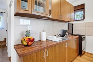 A modern kitchen with wooden cabinets, a stainless steel sink, and a gas stove. - Greenwood Retreat With Hot Tub & Sauna (Sveti Martin na Muri)