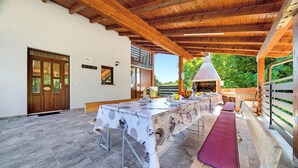 An outdoor dining area with a long table, benches, and a grill. - Greenwood Retreat With Hot Tub & Sauna (Sveti Martin na Muri)