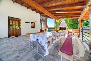 An outdoor dining area with a long table, benches, and a grill. - Greenwood Retreat With Hot Tub & Sauna (Sveti Martin na Muri)